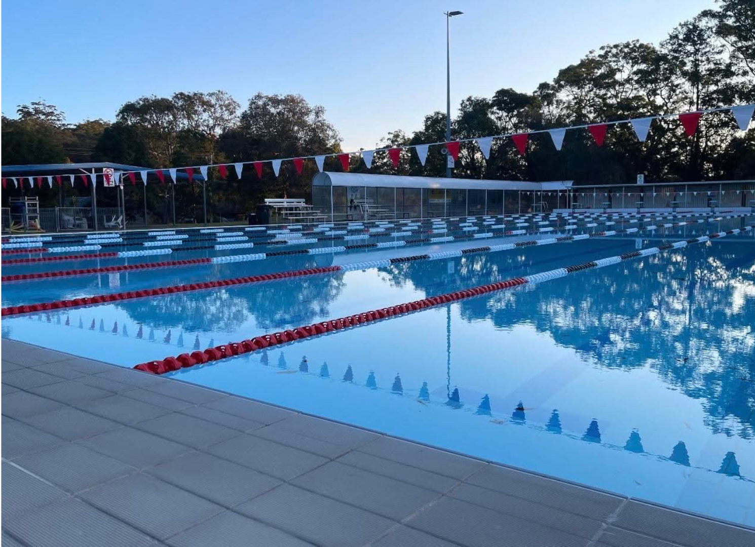 Image shows an empty 50m heated outdoor swimming pool at Tomaree Aquatic Centre in the evening.