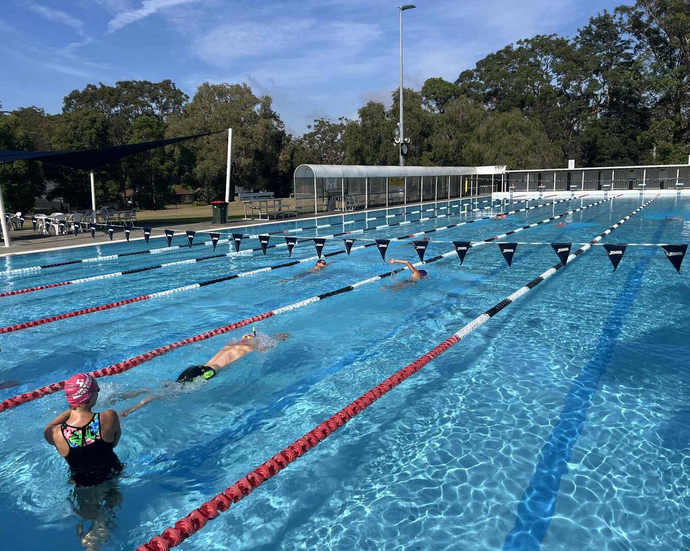 Image shows people swimming in a lane in the 50m outdoor heated swimming pool at Tomaree Aquatic Centre